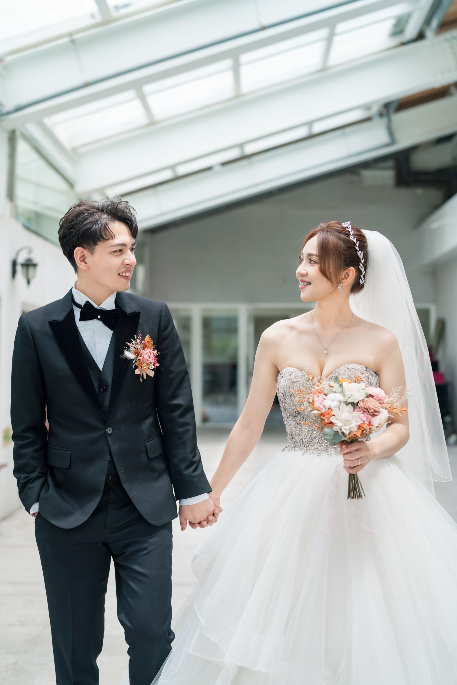 Romantic wedding portrait of couple holding hands in bright indoor venue.