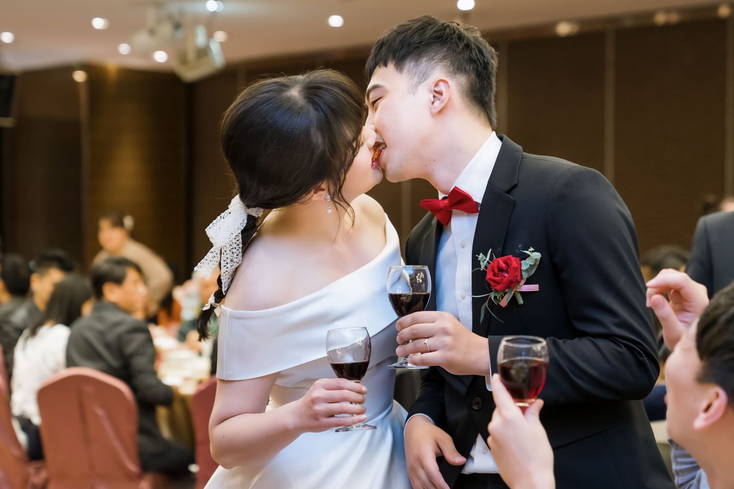 Romantic moment between newlyweds sharing wine during their wedding reception.