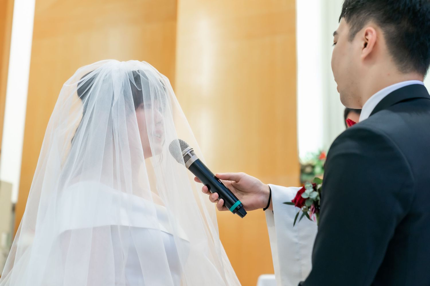Wedding vows being exchanged at an altar decorated with orange and red flowers.