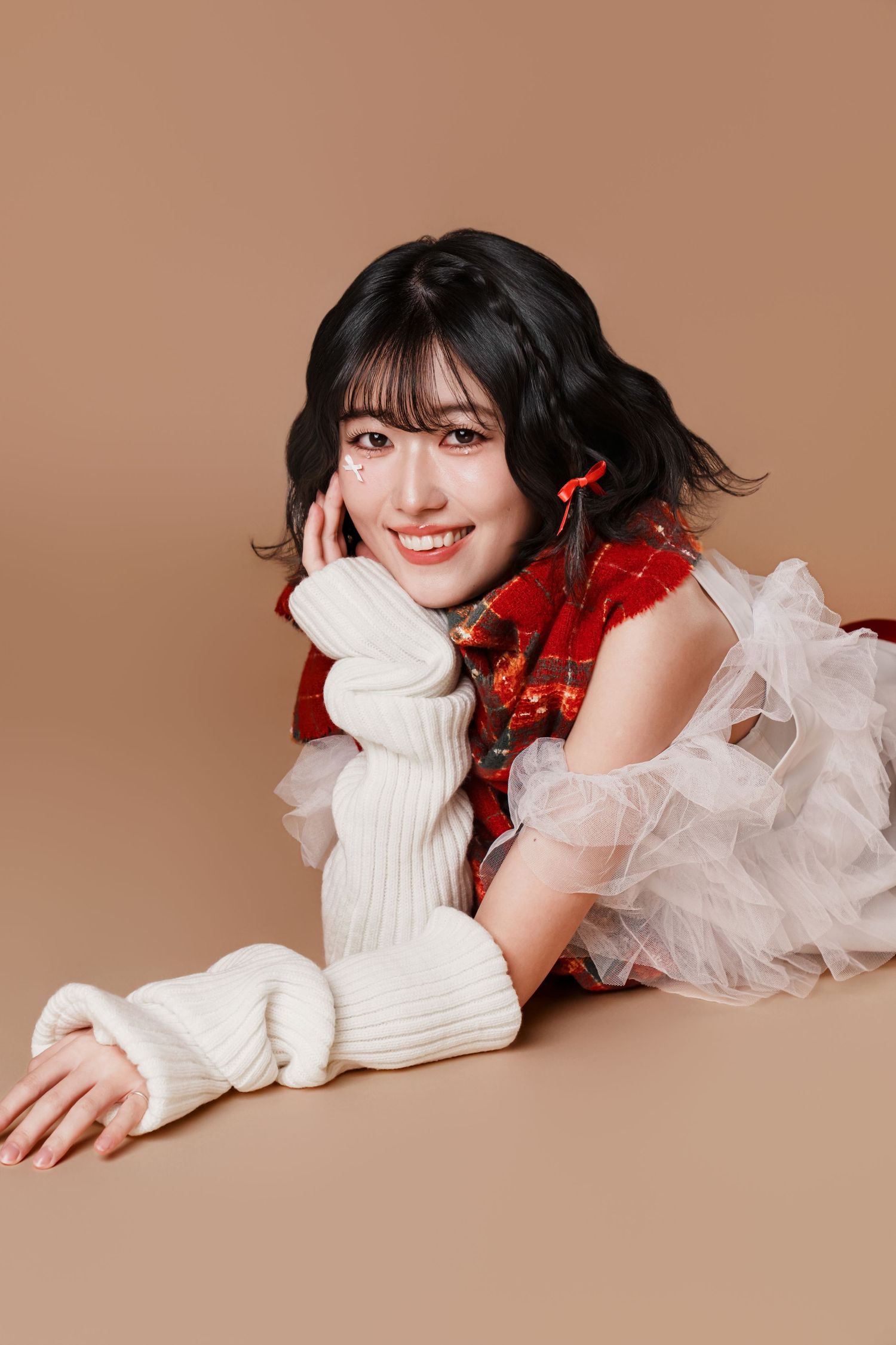 A series of studio portraits showing someone in a white sweater with red holiday decor against a neutral background.
