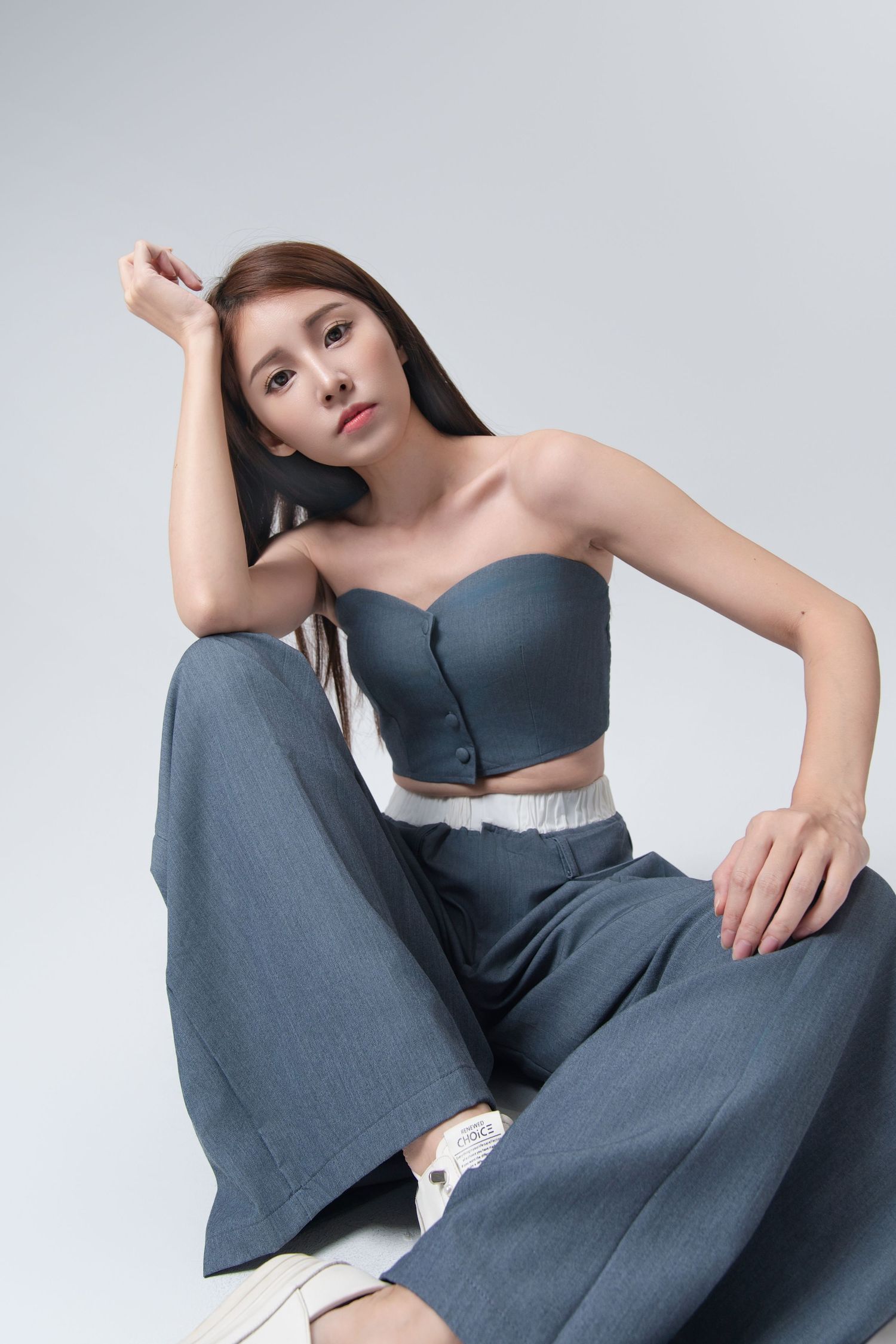 Model in slate blue loungewear set poses elegantly against light background showing modern minimalist fashion style.