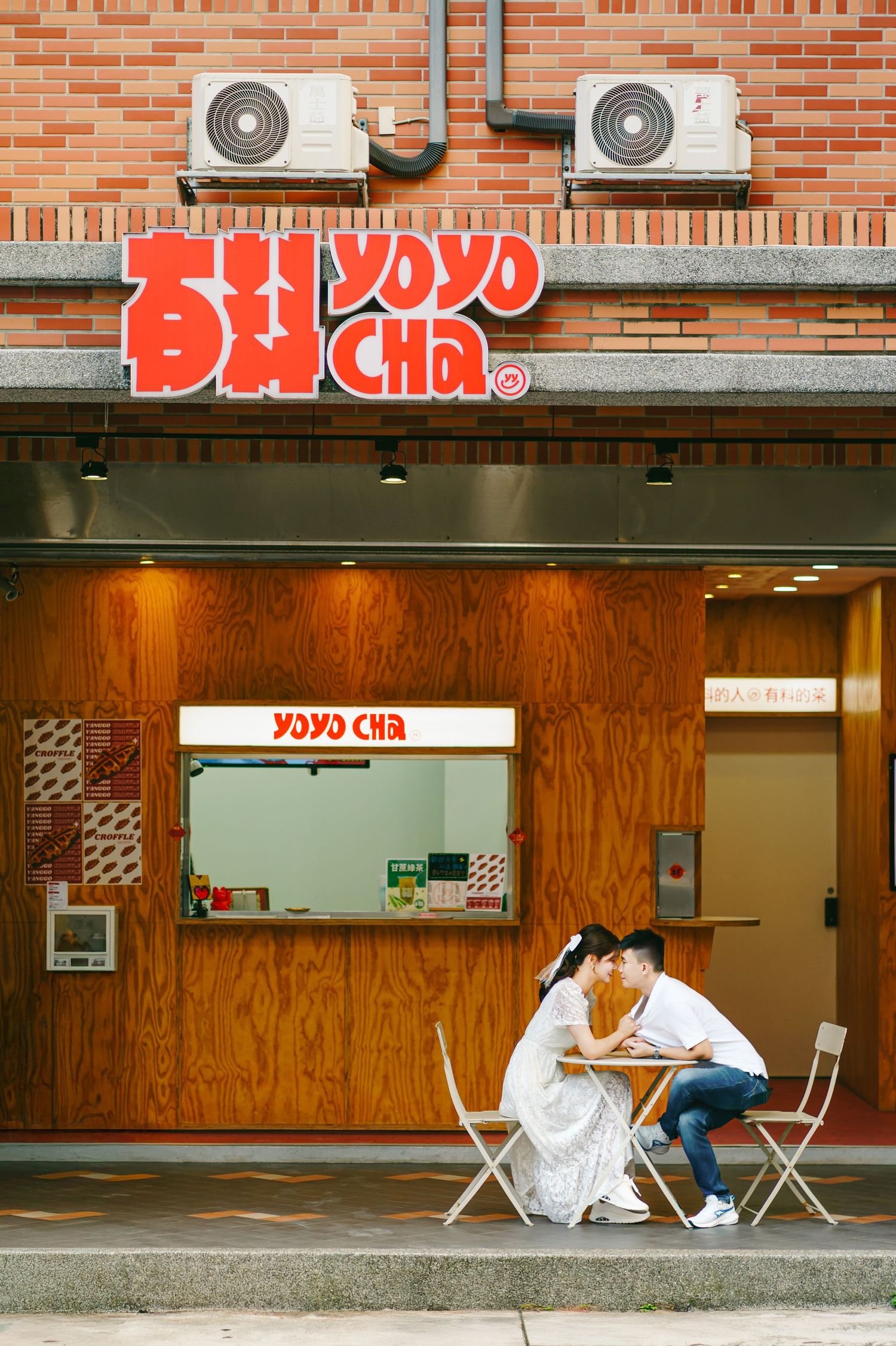A storefront of Yoyo Cha bubble tea shop with two air conditioning units mounted above the red signage.