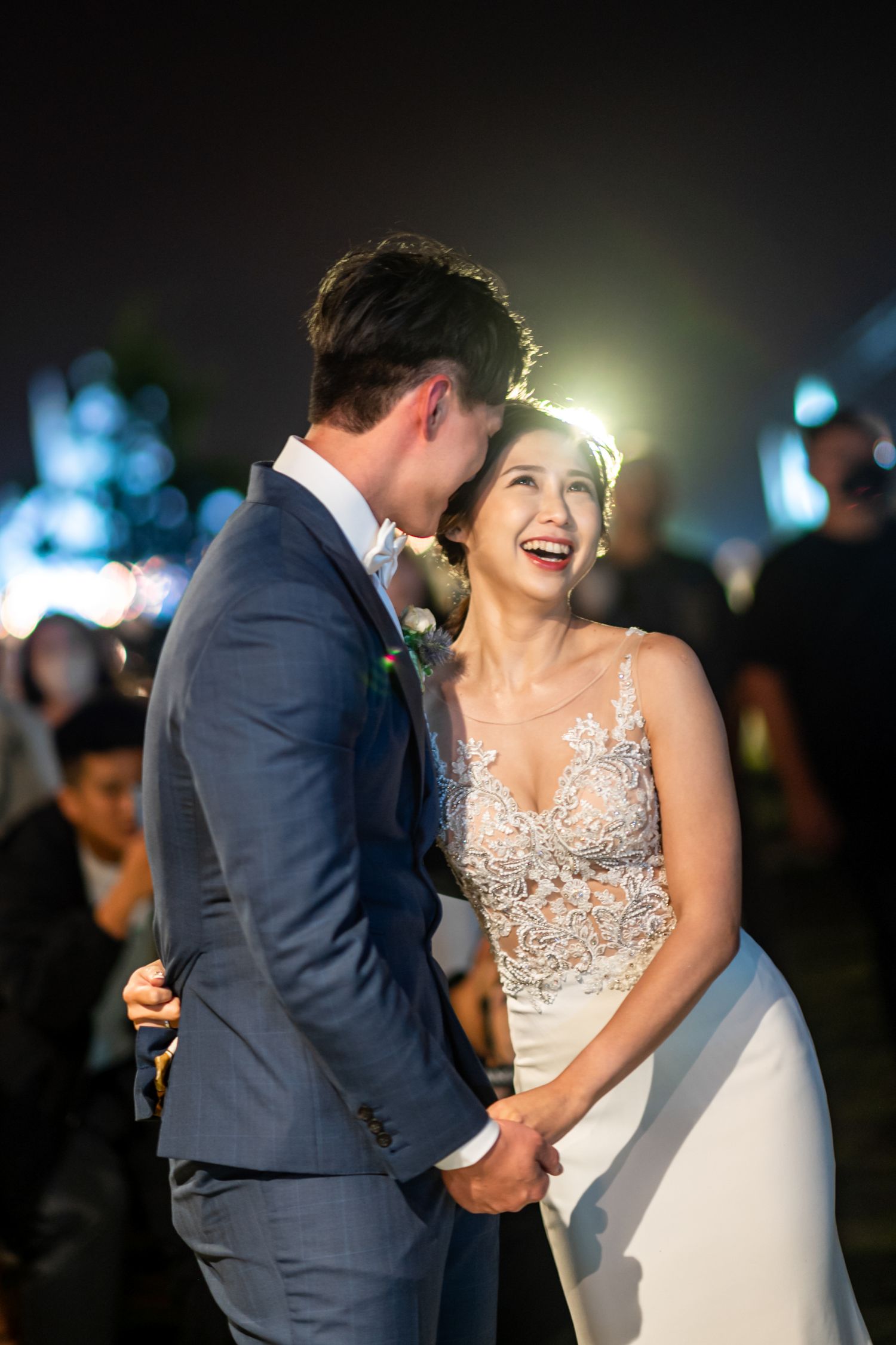 A joyful candid moment between newlyweds sharing laughter at their evening wedding reception.