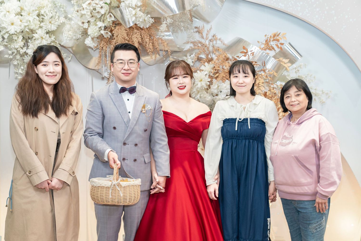 A group of people wearing formal attire including red dresses and suits pose together at an elegant event.