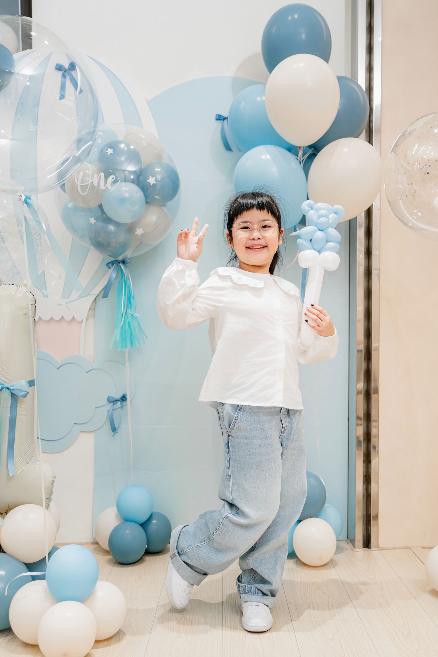 A festive party setup with blue and white balloons creating a joyful atmosphere against a light colored wall.