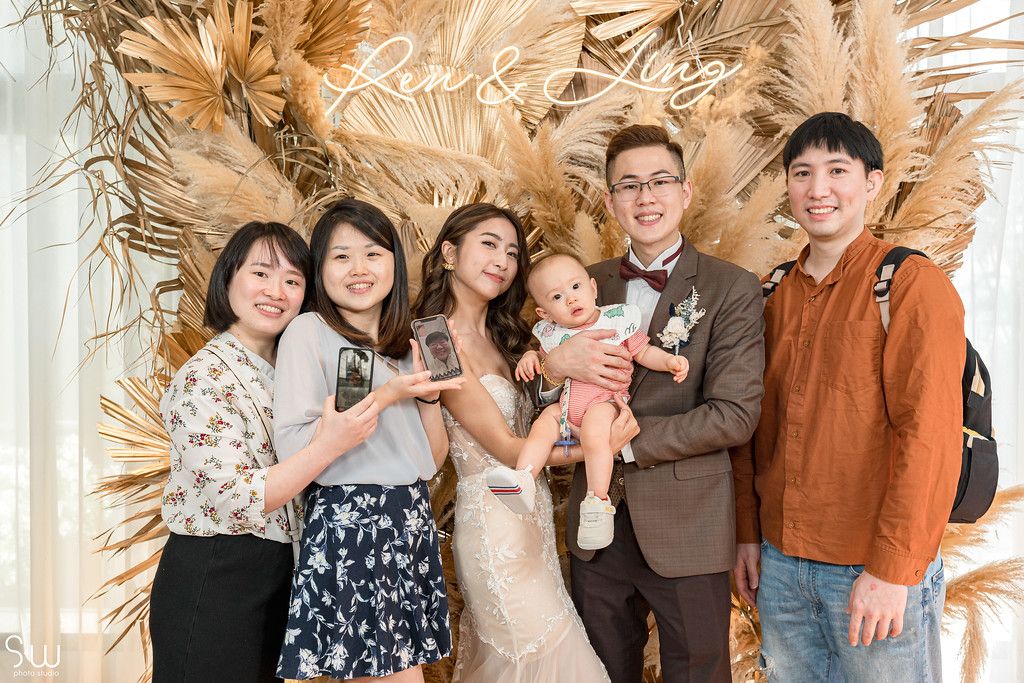 Wedding party poses against dried pampas grass backdrop in indoor venue.