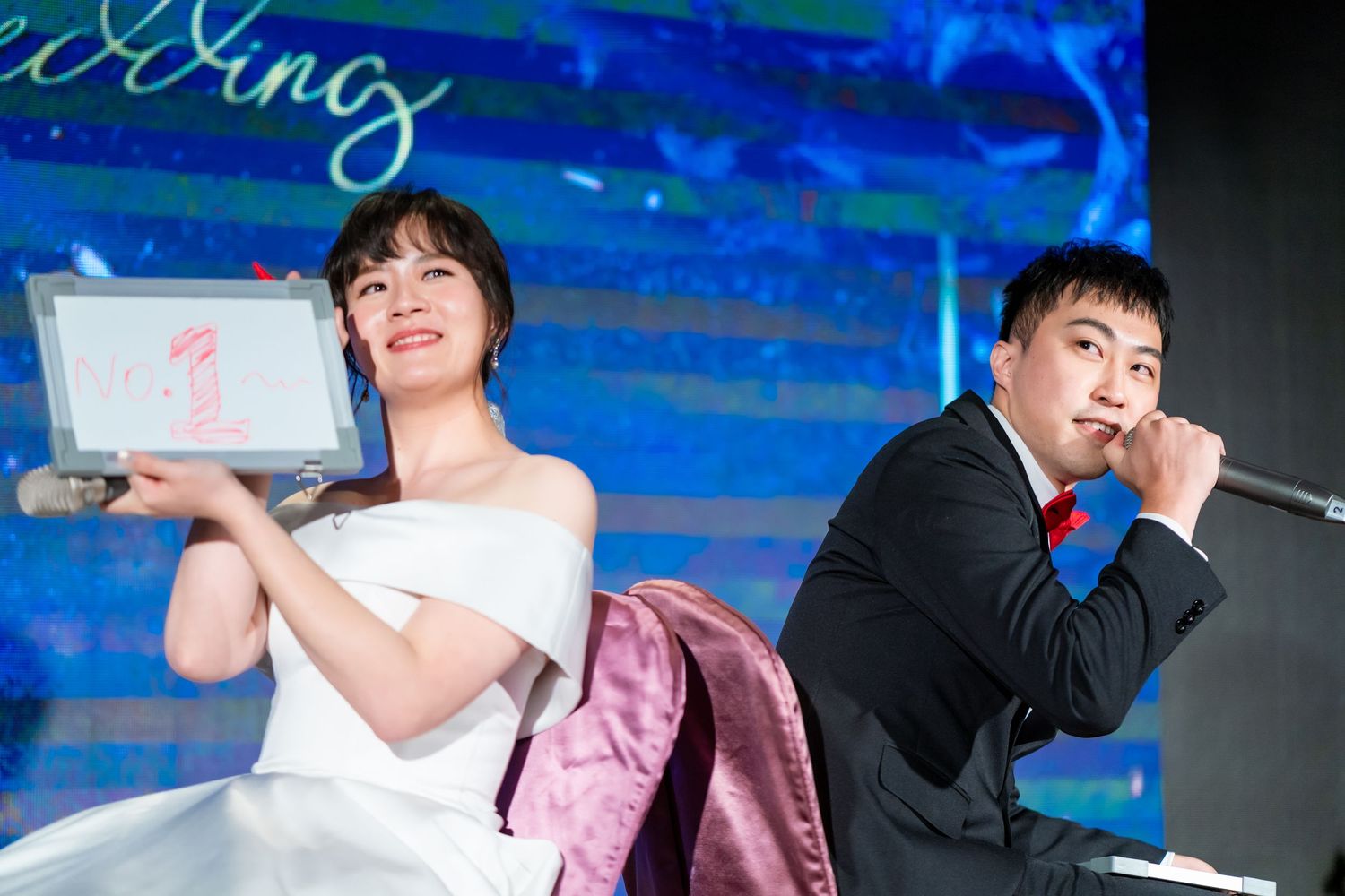 Wedding performers on stage with dramatic blue lighting during an entertainment segment.