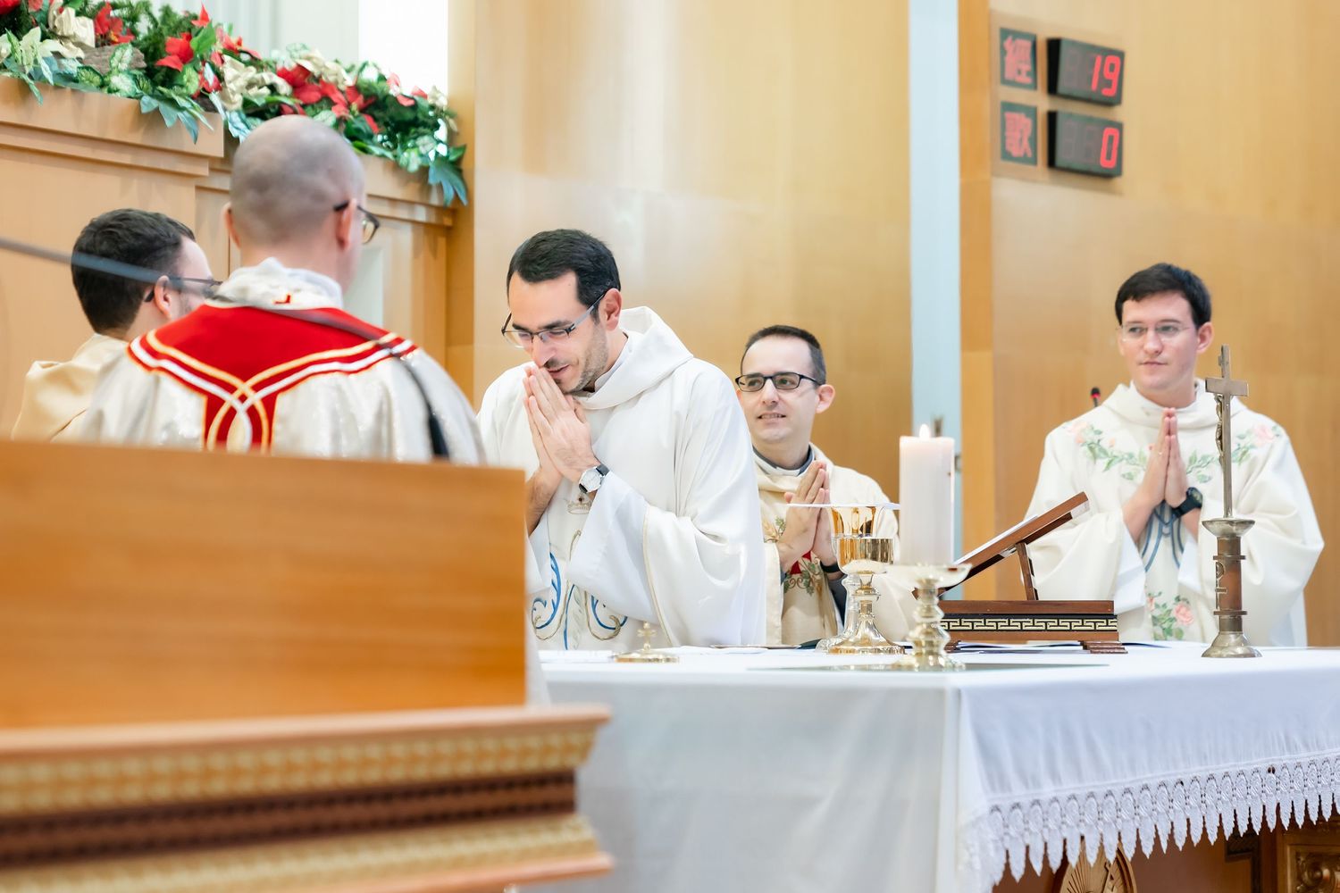 Catholic priests celebrating mass at decorated church altar.