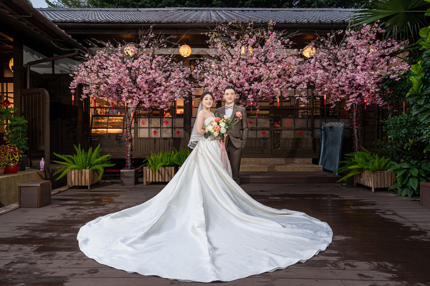 Beautiful spring wedding ceremony backdrop with illuminated cherry blossoms and elegant gown with flowing train.