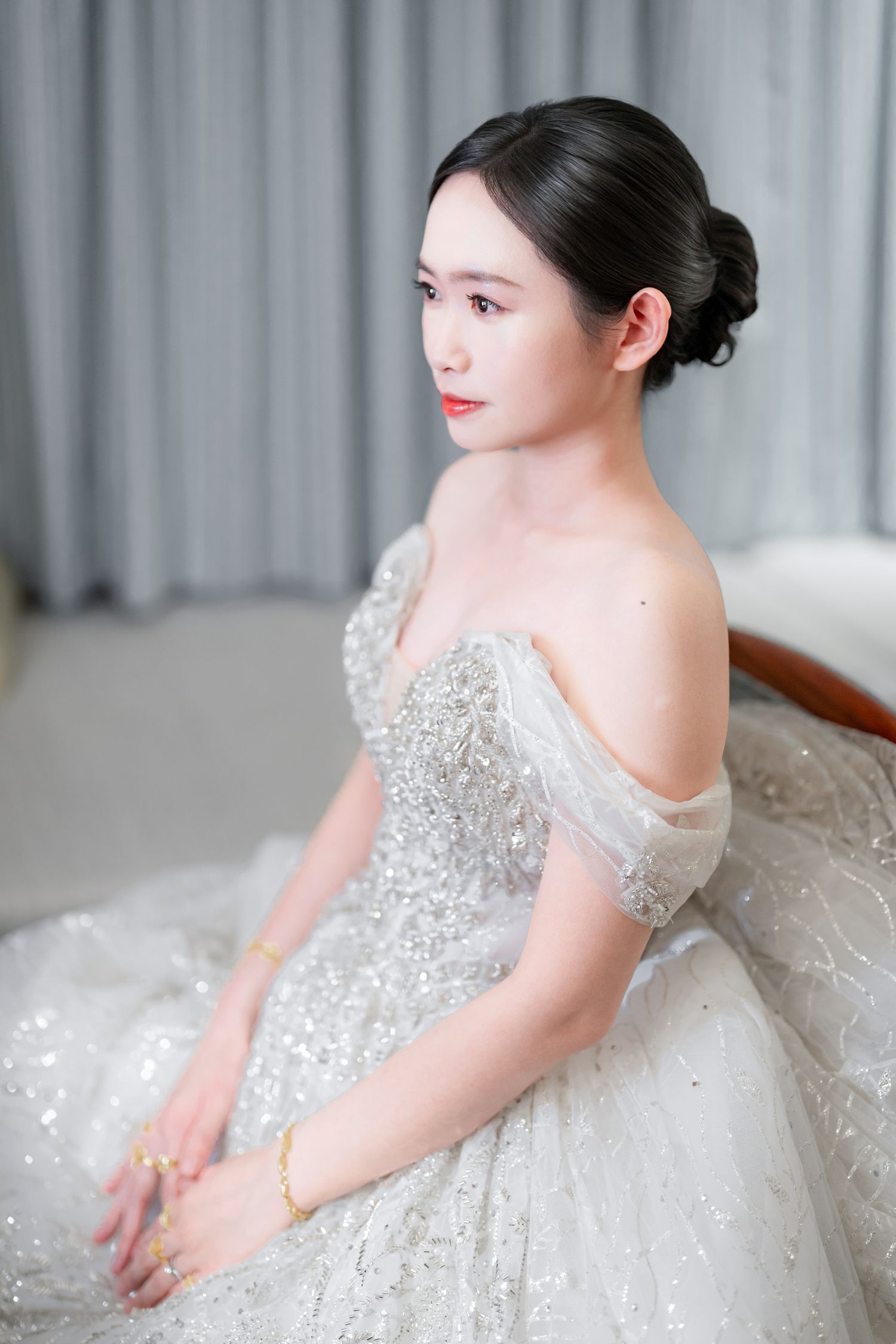 A bride in a sparkling white ball gown with crystal embellishments poses elegantly in a bridal portrait series.