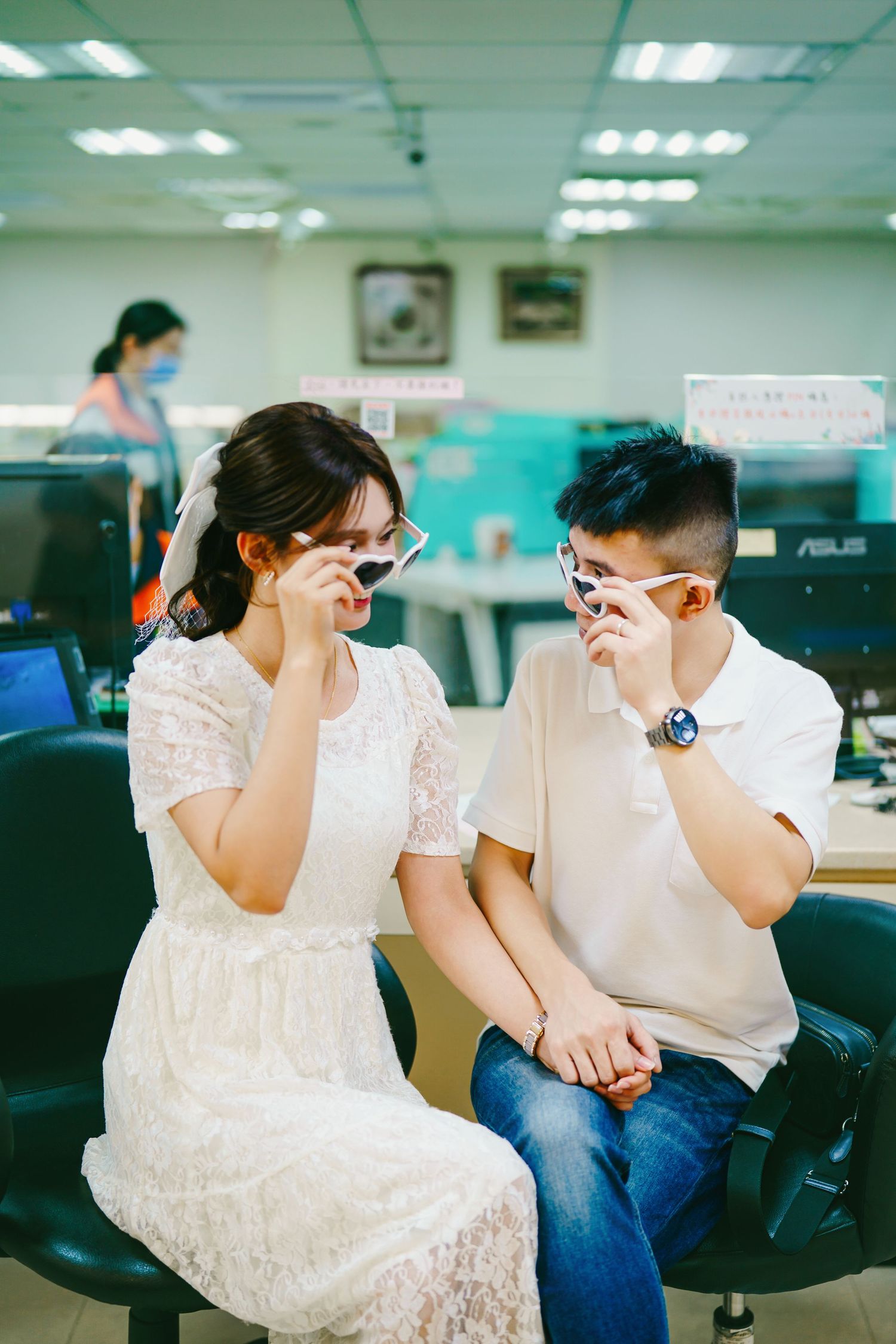A couple sitting in office chairs share a lighthearted moment together in a bright workspace environment.