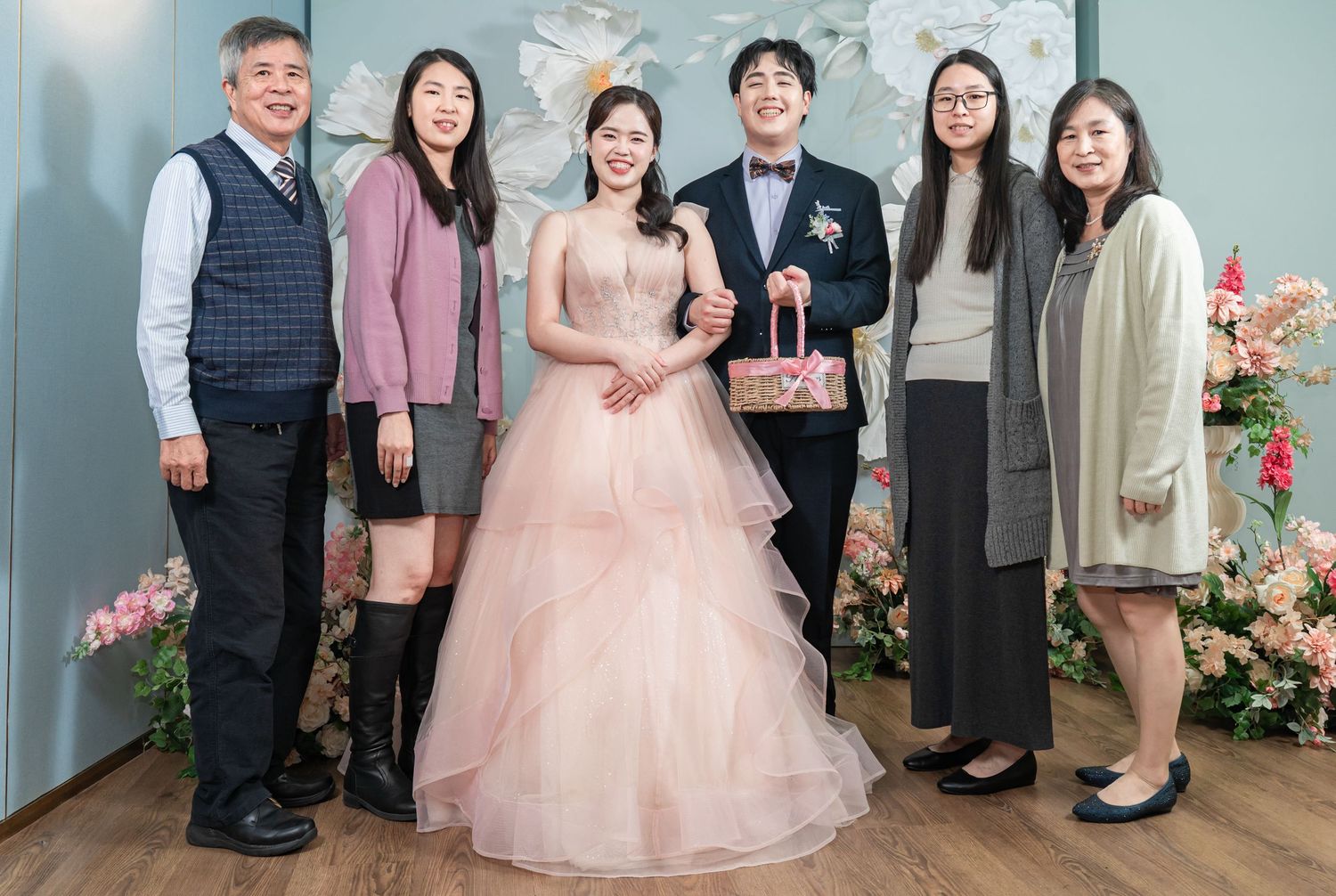 A group poses together at a formal celebration with someone wearing a pink tulle ballgown in an elegant indoor setting.