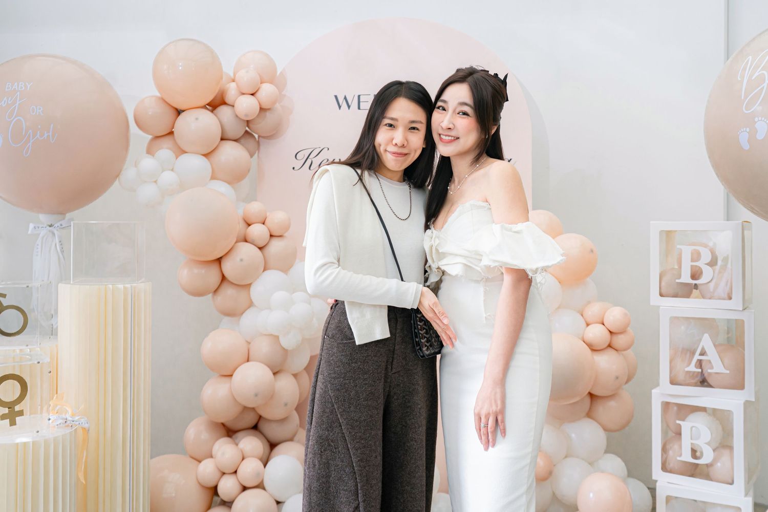 Wedding party decor with blush pink balloon garlands and white accents in an elegant indoor venue setting.