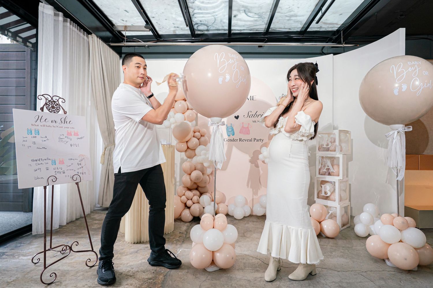 Elegant wedding decor featuring blush pink balloons and white accents in a modern indoor venue.