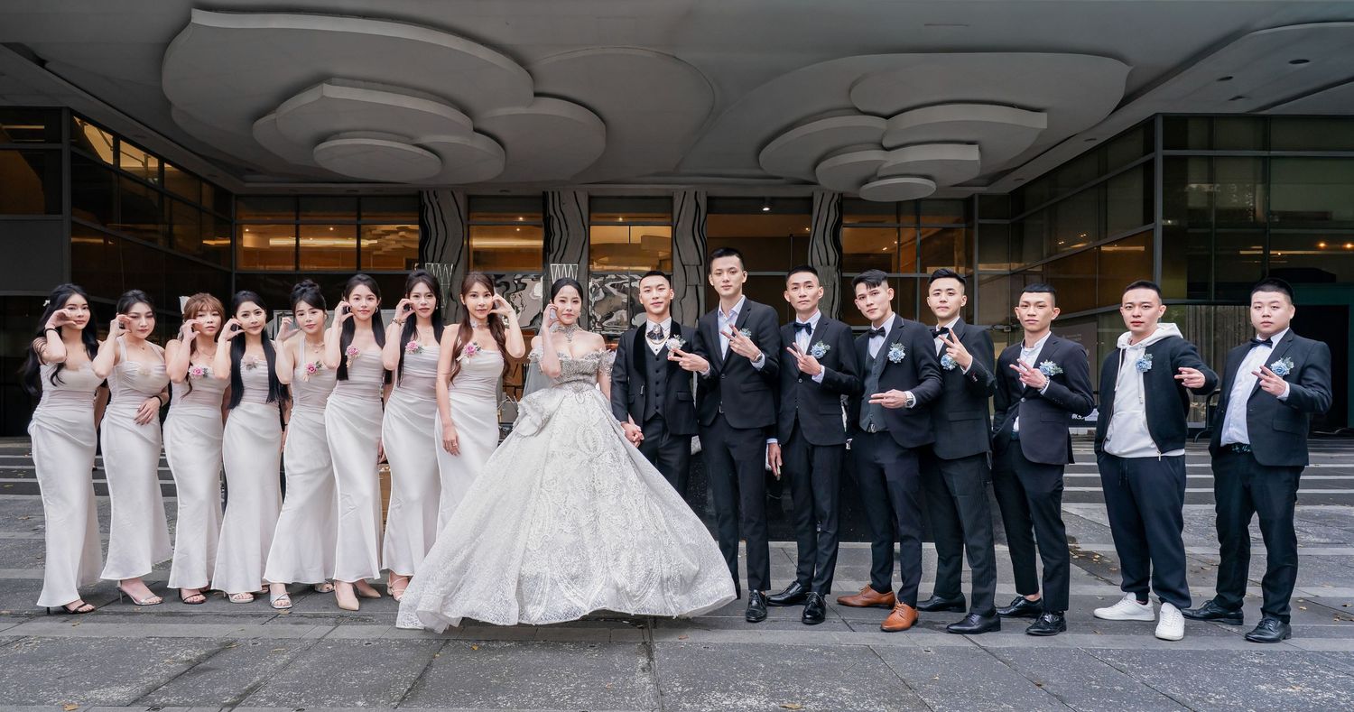 Wedding party members pose together in formal attire along a modern architectural walkway.