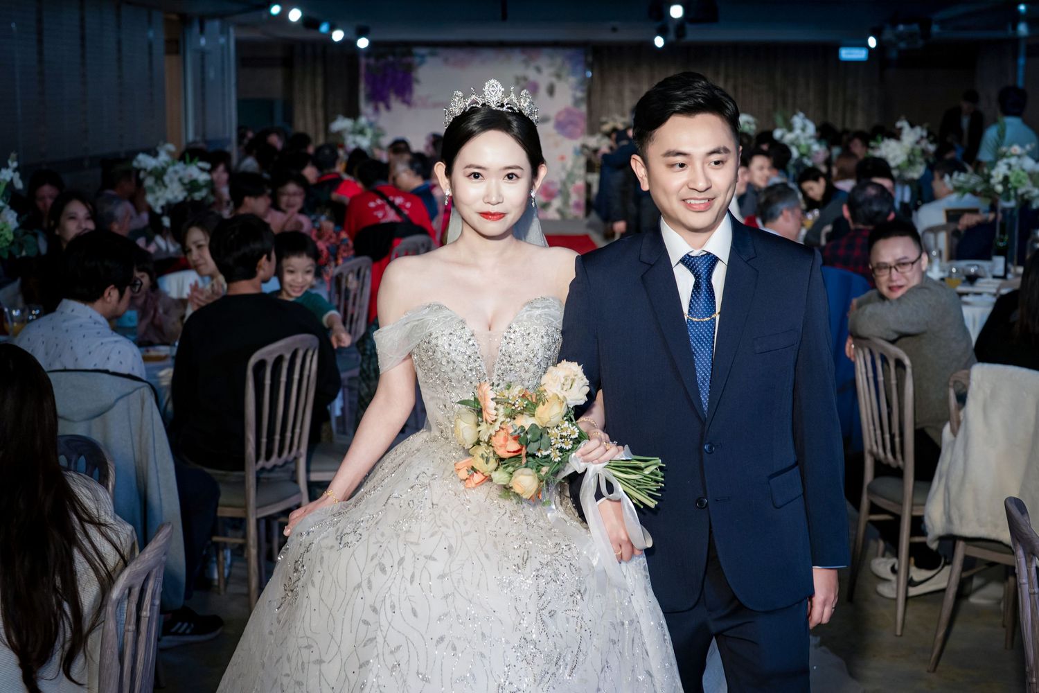 A couple in formal wedding attire poses for photos during their reception celebration.