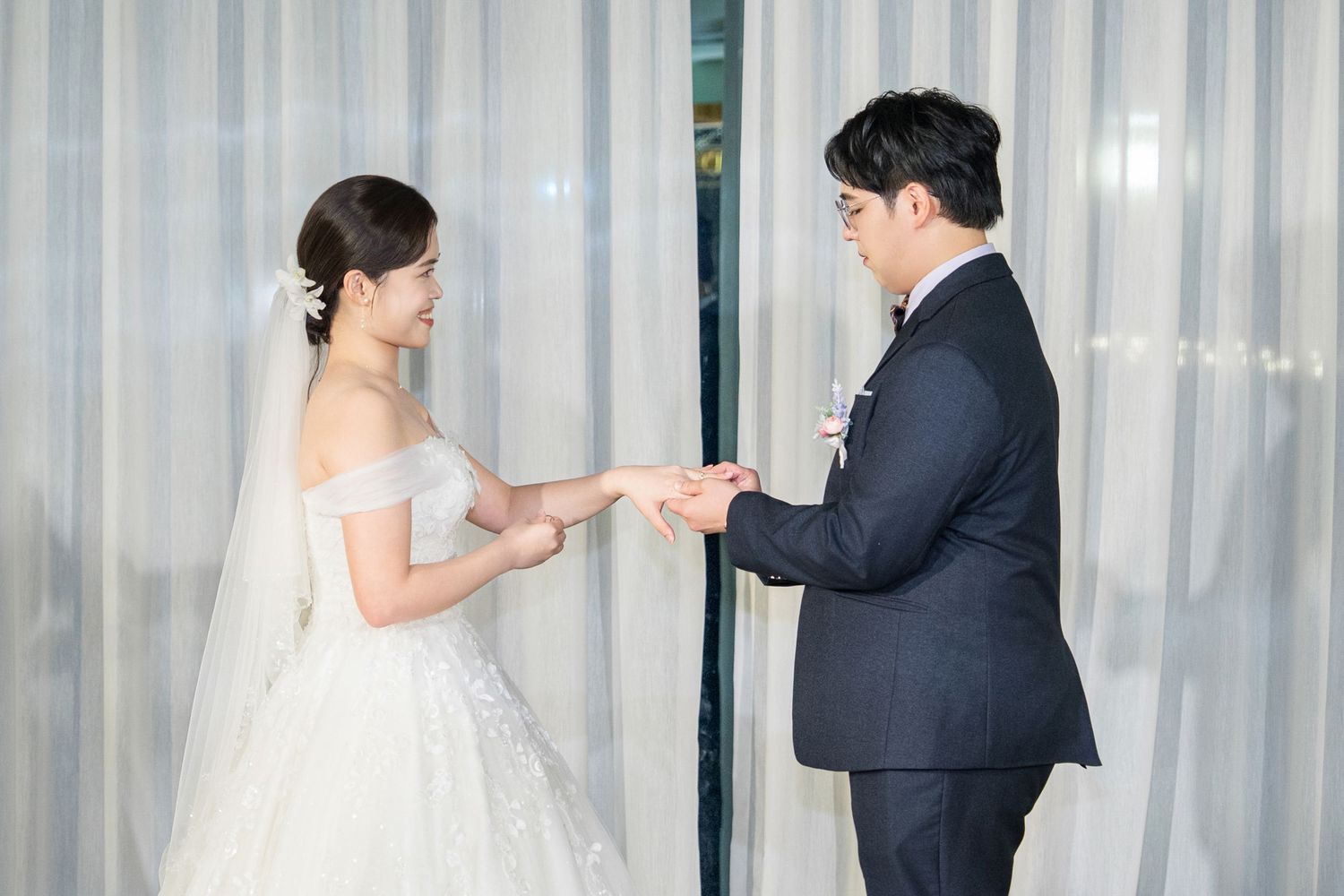 A bride and groom share an intimate first dance moment in front of sheer white curtains during their wedding reception.