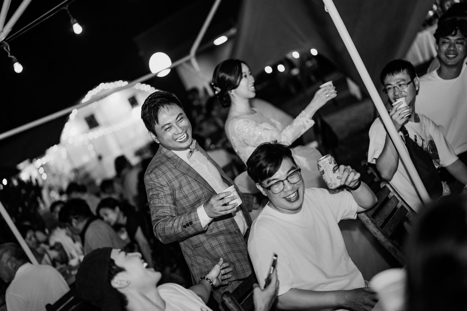 Wedding guests dancing and celebrating on a lively dance floor under indoor lighting at a reception celebration.