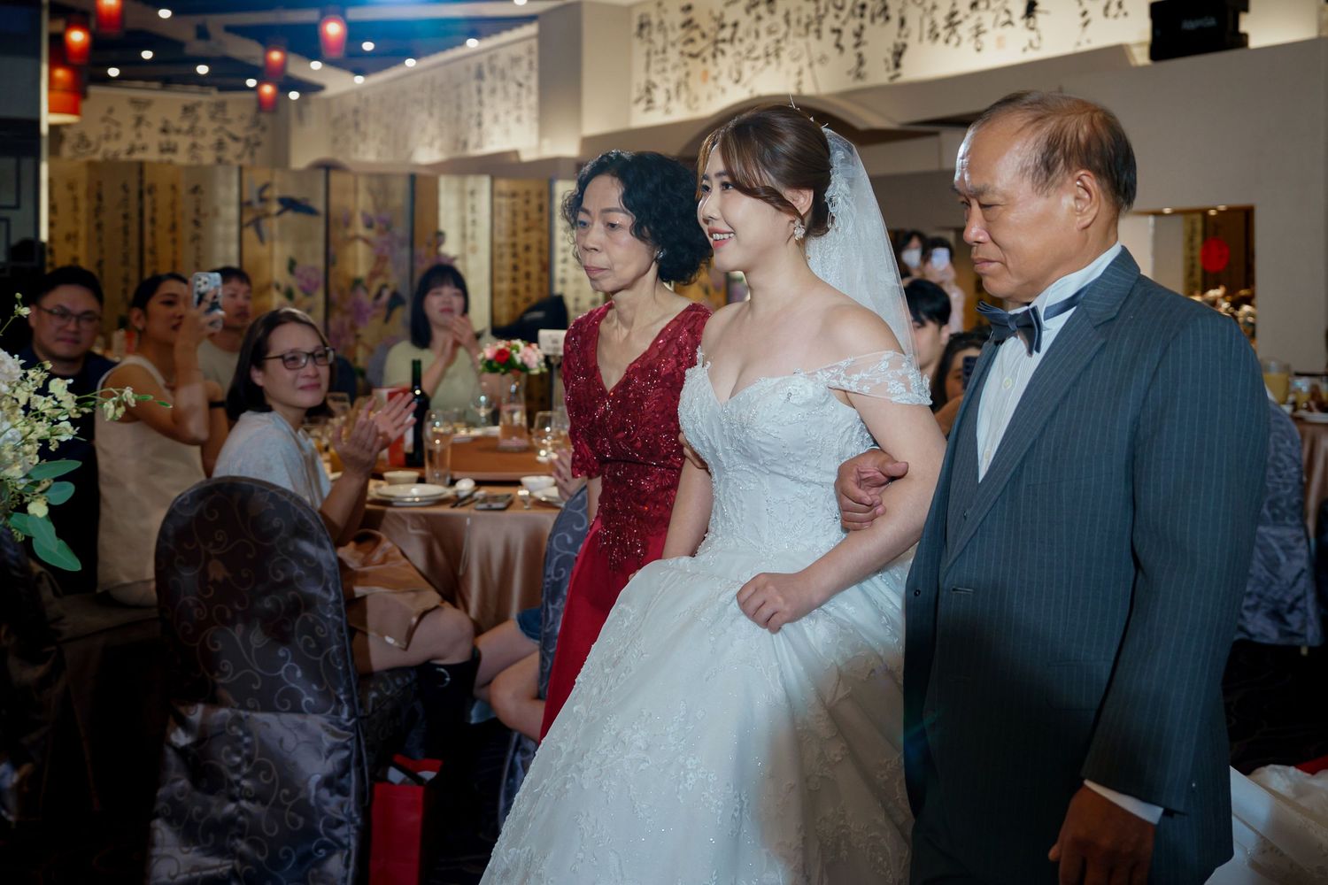 A couple dances together at their wedding reception while guests watch and celebrate in the background.