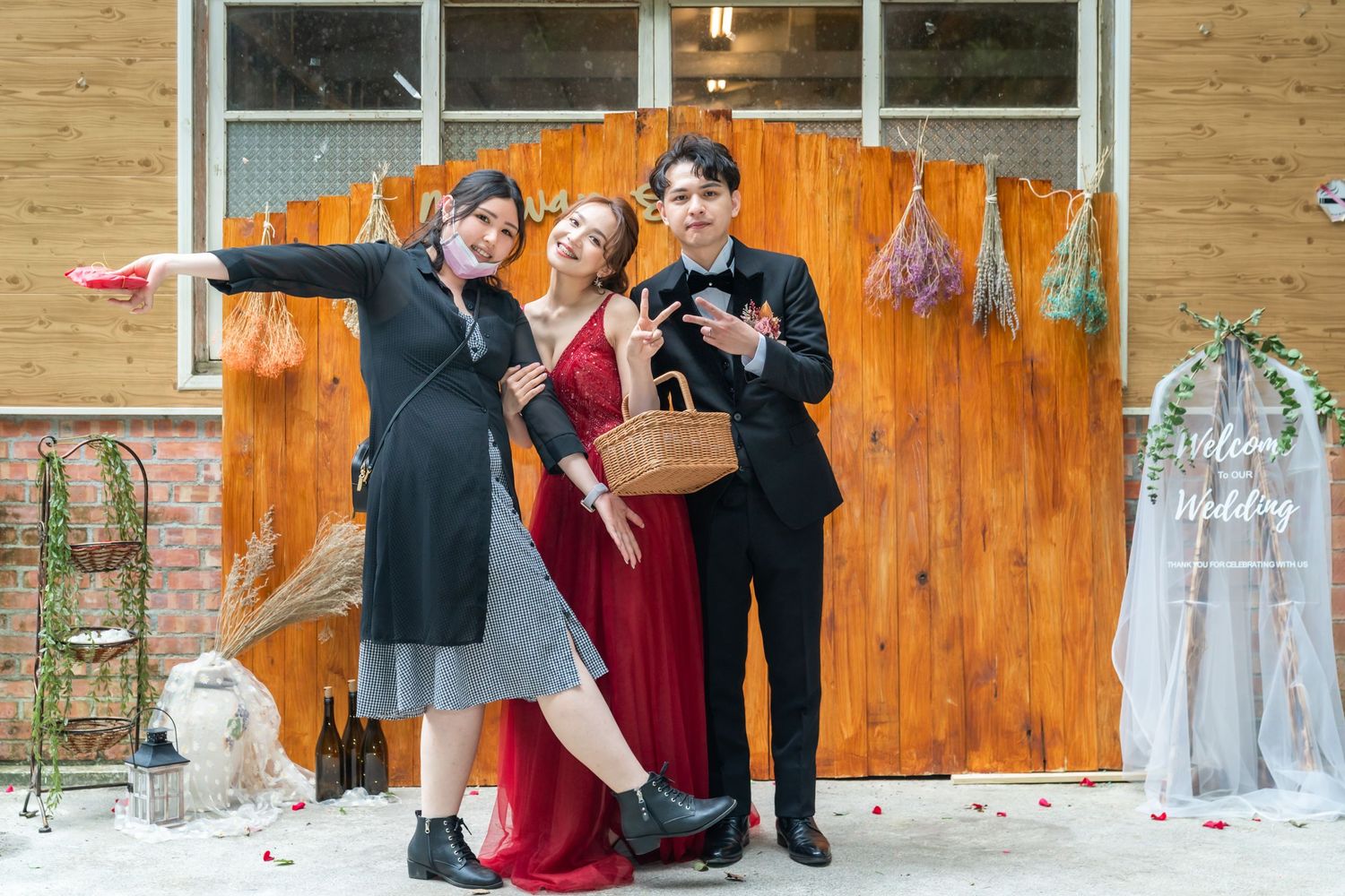 A festive gathering against an orange wooden backdrop with elegant attire and a picnic basket.