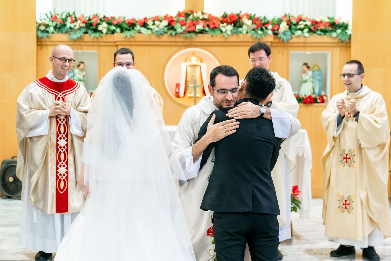 A Catholic wedding ceremony reaches its conclusion as clergy bless the couple.