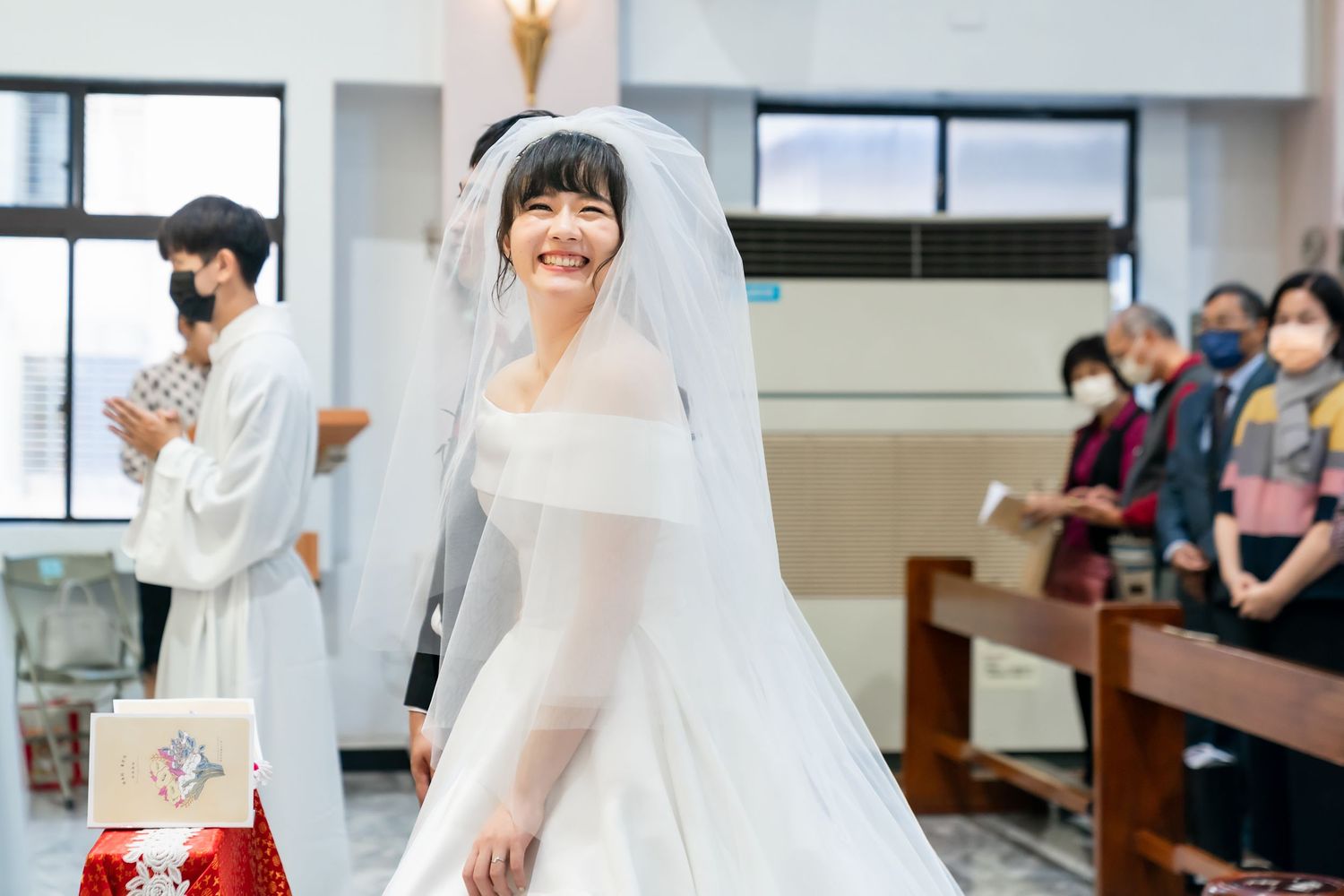 Bride in white dress and veil during church ceremony.