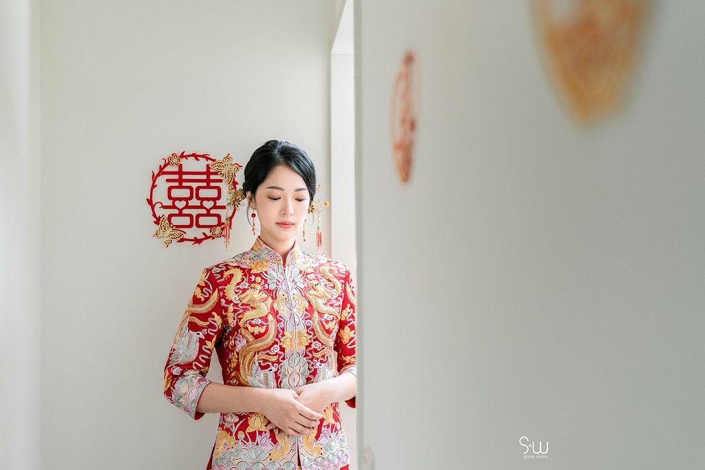 Traditional Chinese dress with red and gold dragon patterns photographed in an interior setting.