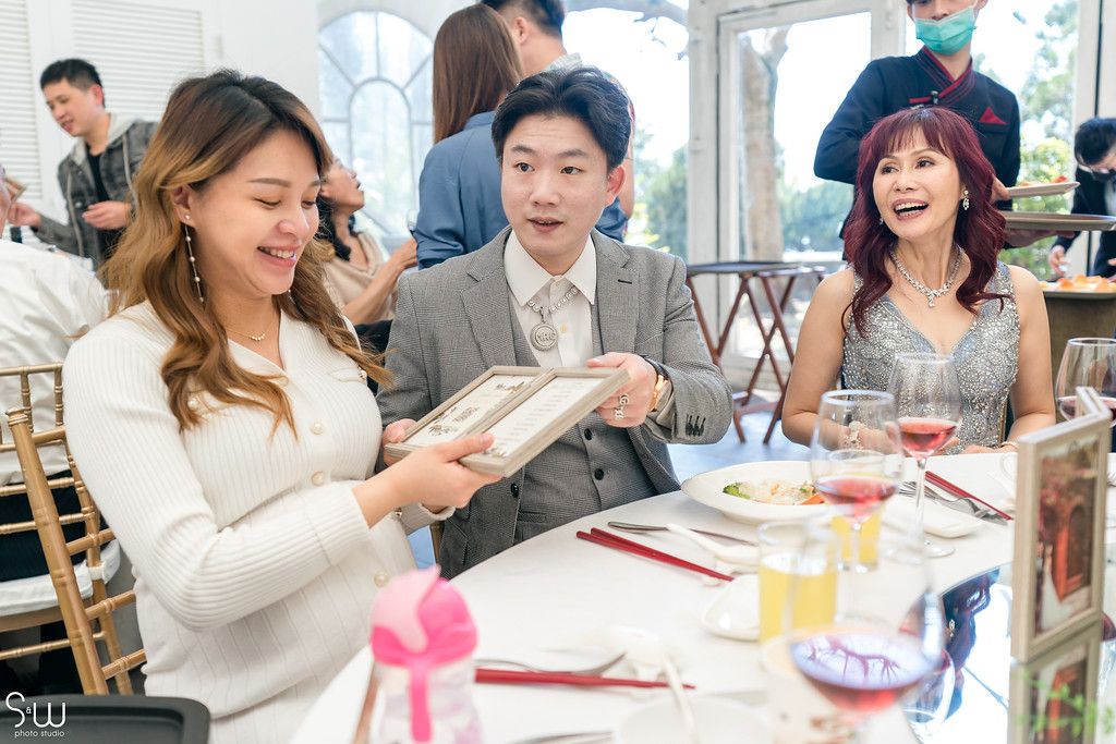 Guests at a reception table sharing laughter while looking at something together.