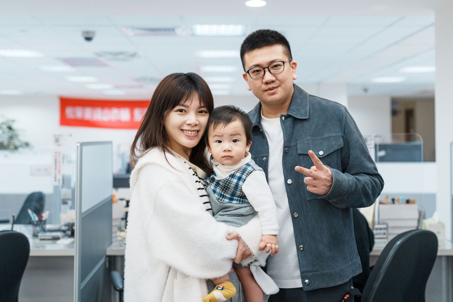 Family members share a warm moment together in a modern office space with white interior and natural lighting.