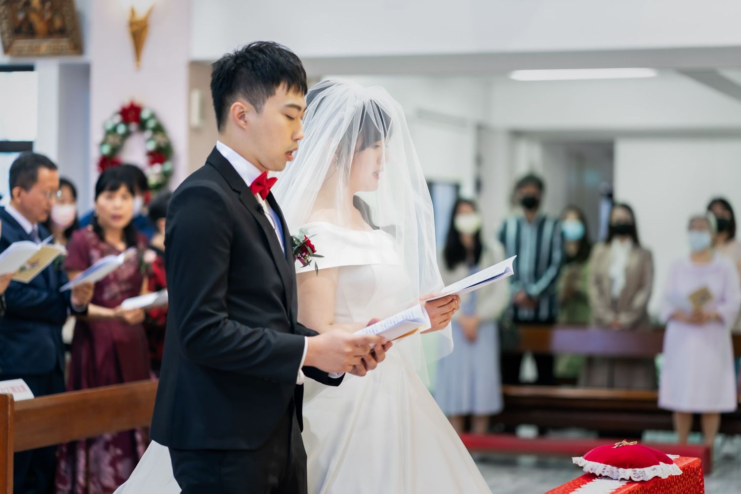 Wedding ceremony in church with couple reading from service books.