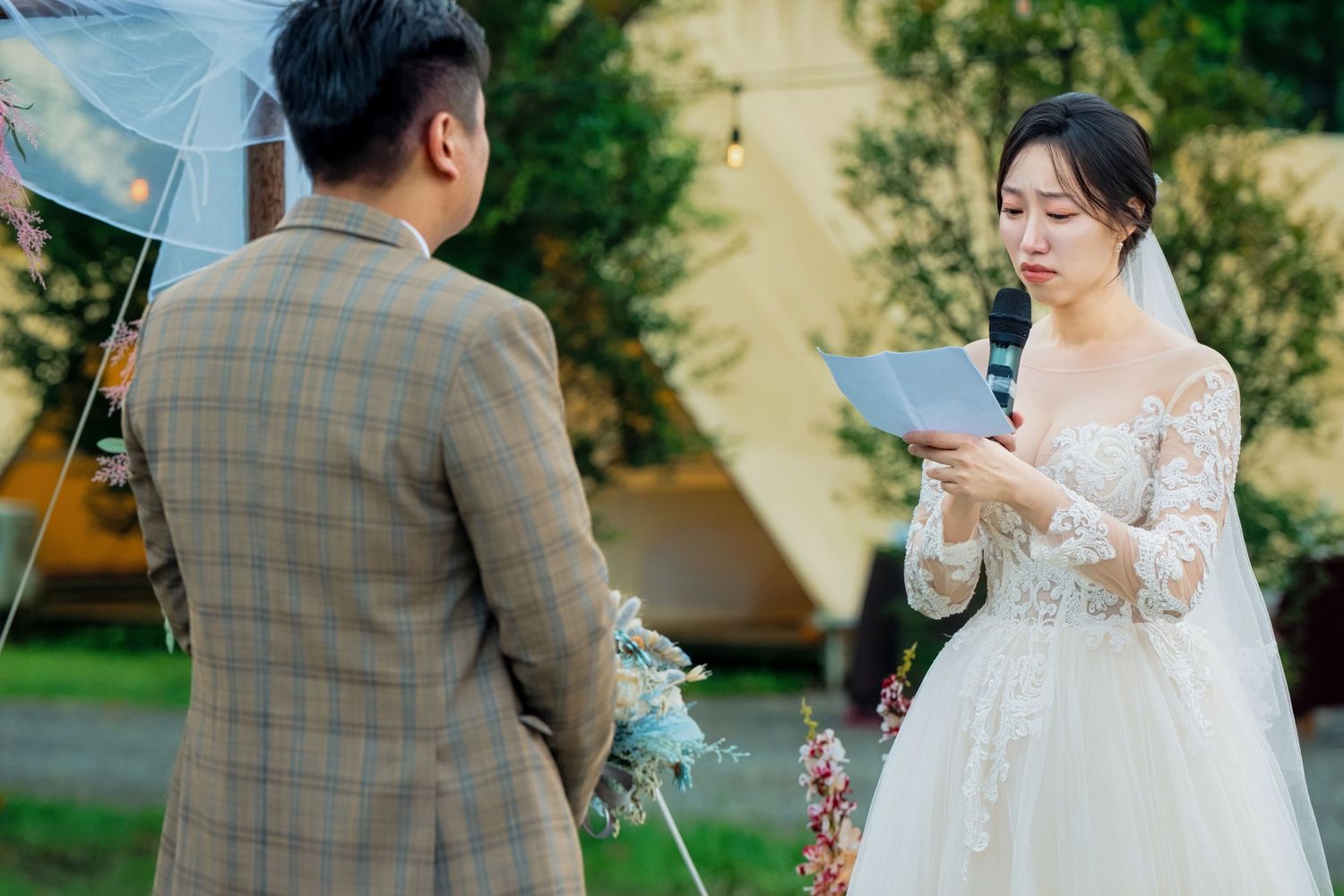 Bride and groom sharing a romantic umbrella moment in a lush garden during their outdoor wedding ceremony.