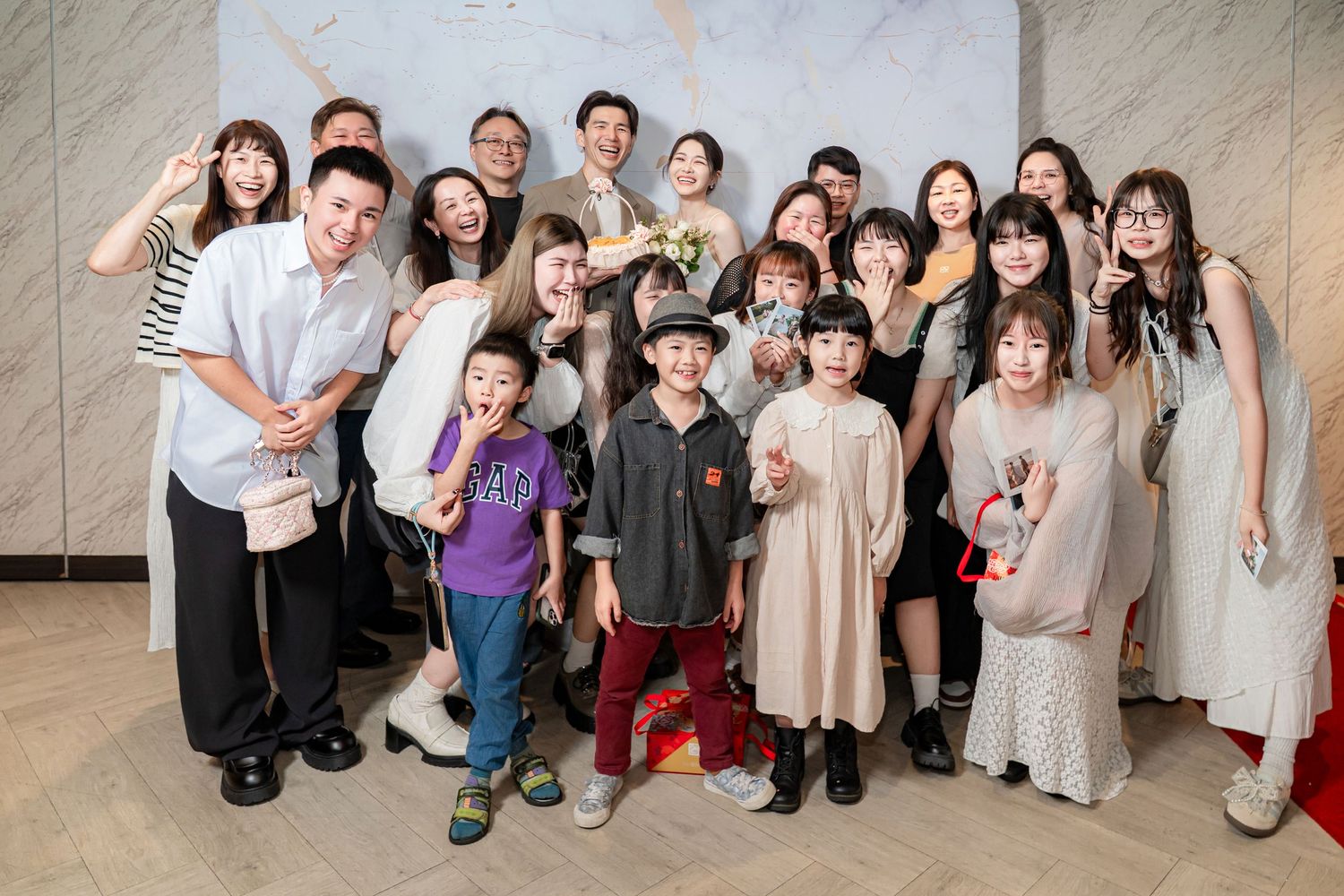 A group of people wearing casual attire pose together for a group photo in front of a textured wall.