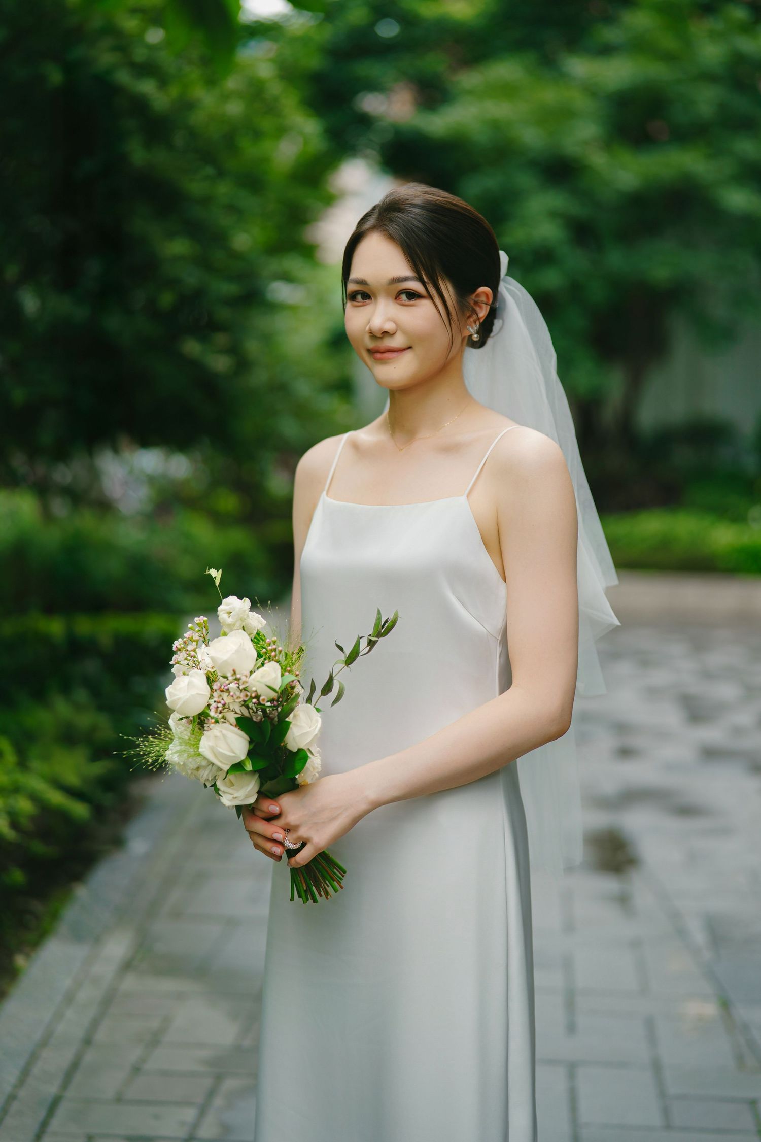 Four similar wedding photos show a bride against green foliage while holding a white rose bouquet in an outdoor setting.