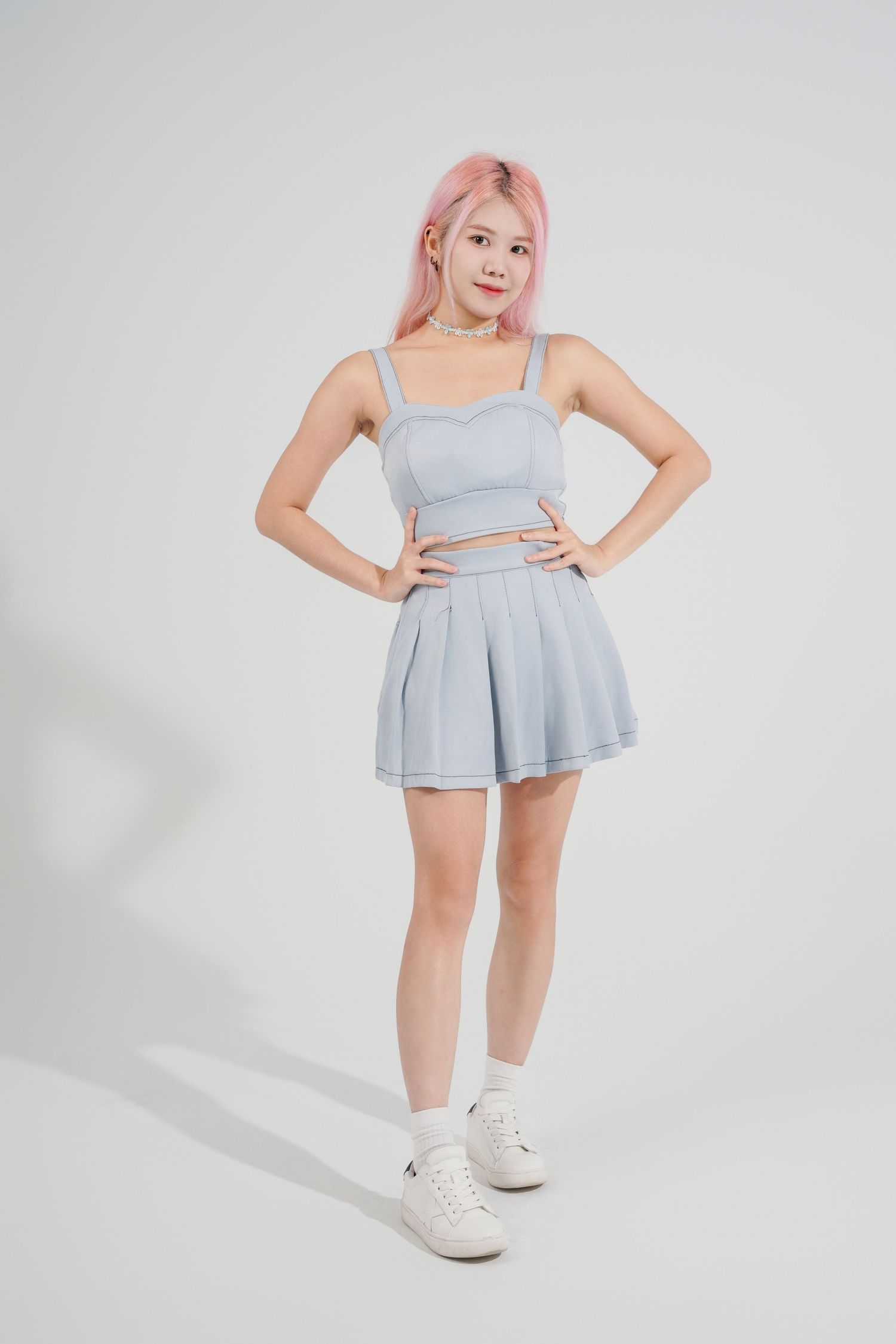 Model in light blue tennis skirt and crop top set with white sneakers poses against white background from multiple angles.