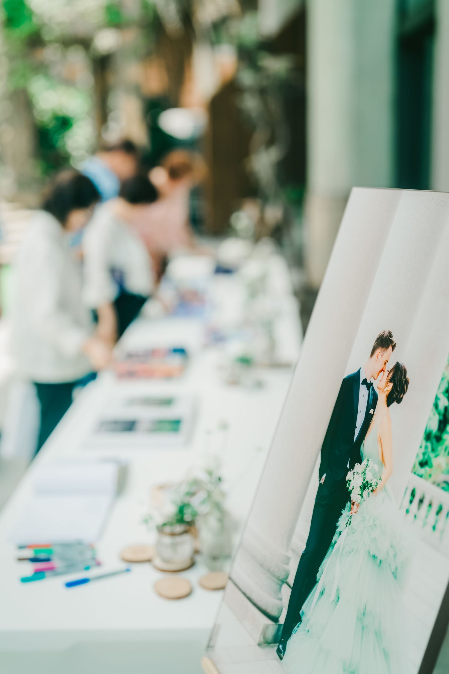 Multiple photo prints arranged in a row show a romantic wedding scene with green accents and blurred edges.