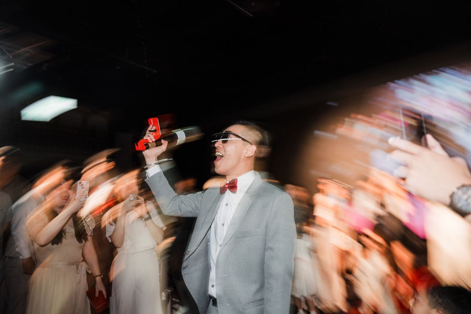 Motion blur captures energetic performance on stage with singer in light gray suit holding microphone under venue lighting.