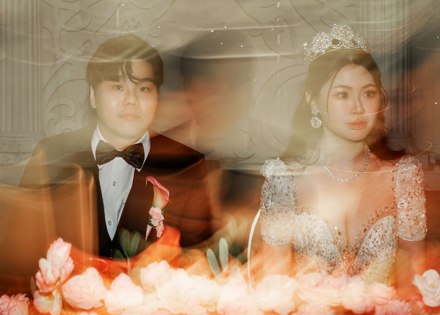 A dreamy, artistic wedding photo with blurred motion effects and warm orange lighting behind candles on a table.