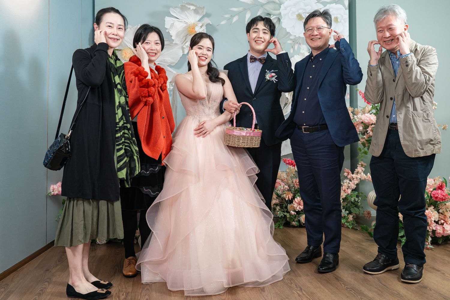 A wedding celebration scene with people gathered together in a bright indoor setting wearing formal attire.