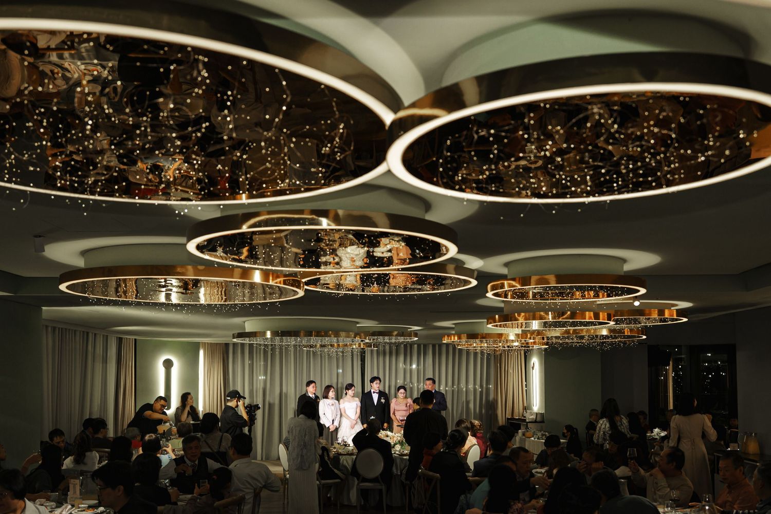 A modern ballroom with circular chandeliers and elegant lighting creates a sophisticated atmosphere for events.