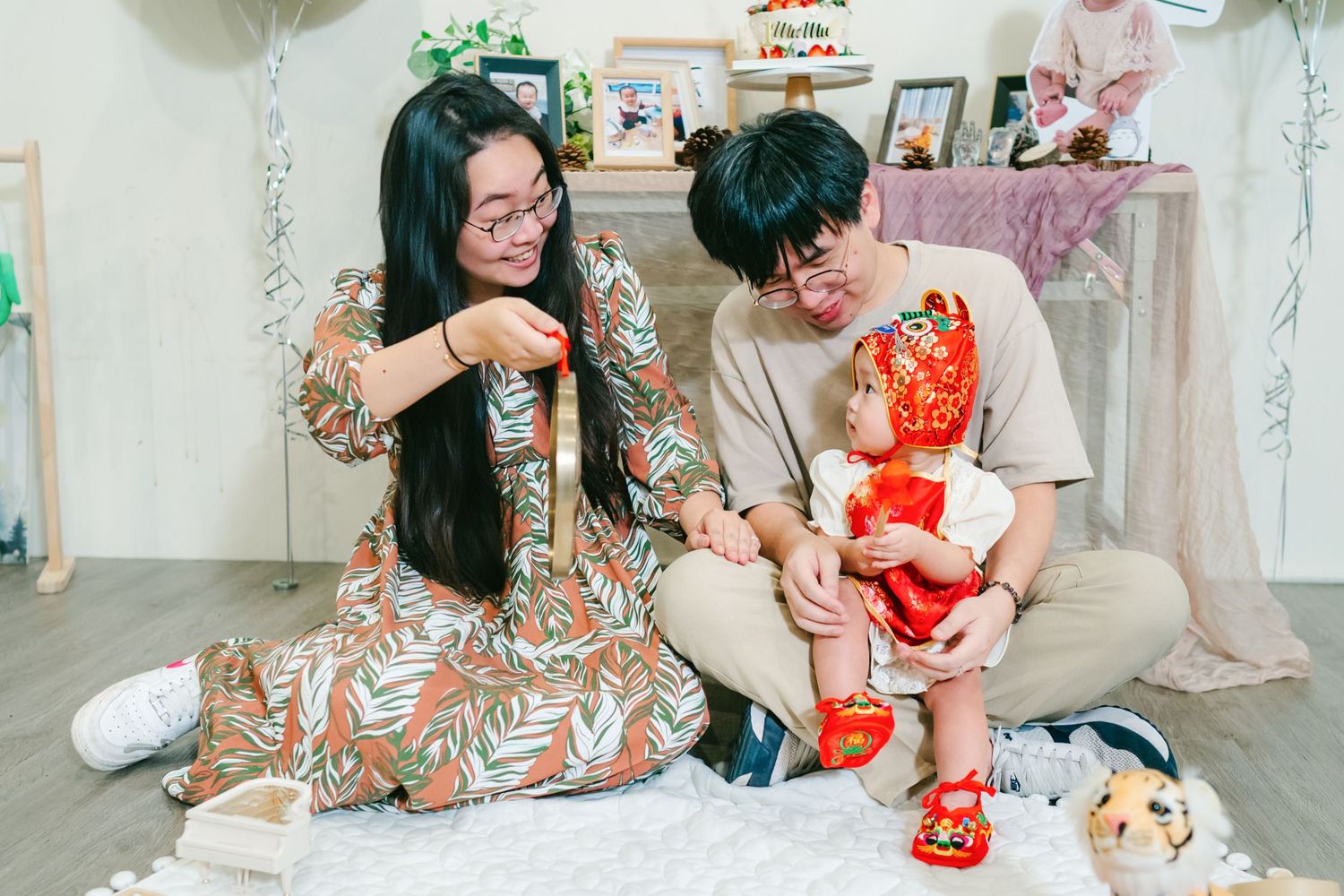 Two people in casual attire sit on floor enjoying snacks and beverages during a cozy indoor celebration.
