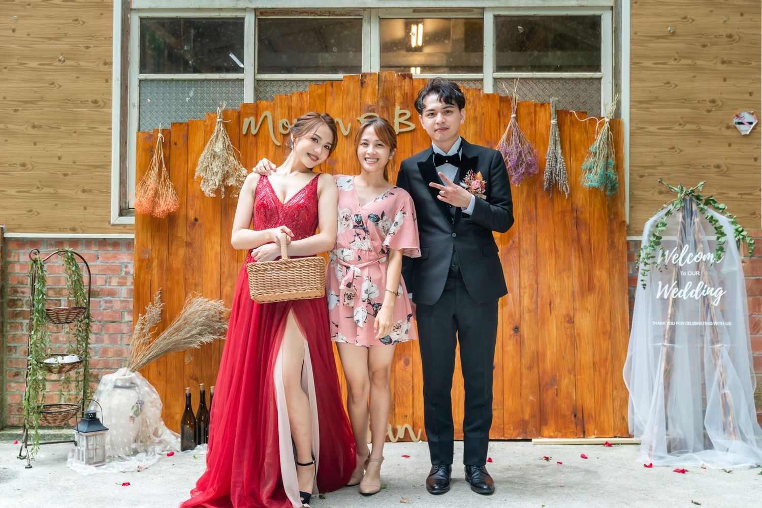 Three people pose together against an orange backdrop with decorative elements and a picnic basket.