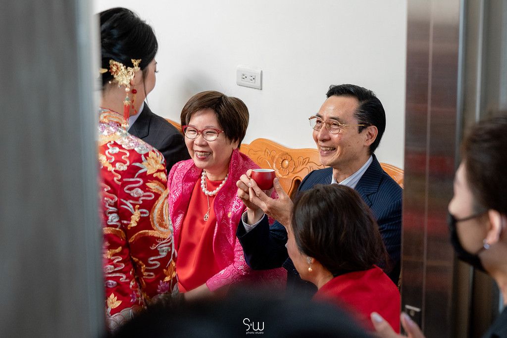 Joyful gathering during Chinese tea ceremony with family members in red attire.