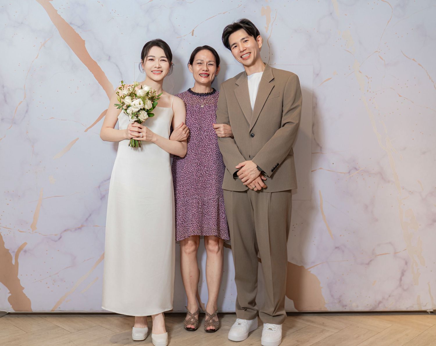 A sequence of family portrait shots showing three people posing together against a marble-textured wall.