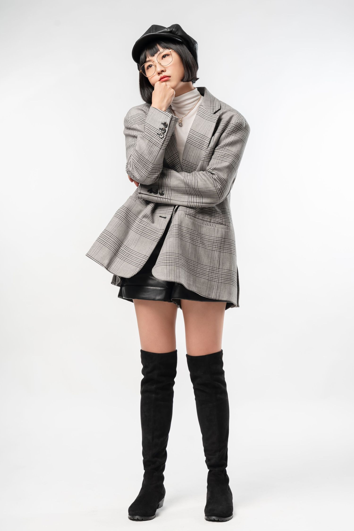 Fashion model in grey plaid blazer and black thigh-high boots poses against white background in four different stances.