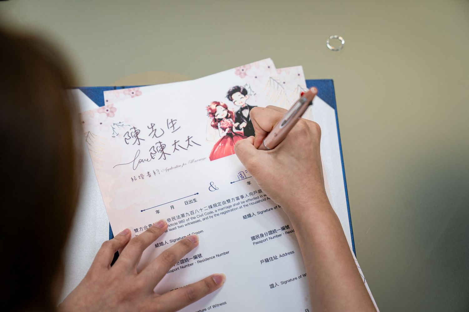 A hand writes with a pen on white paper, showing a close-up view of handwriting in progress.