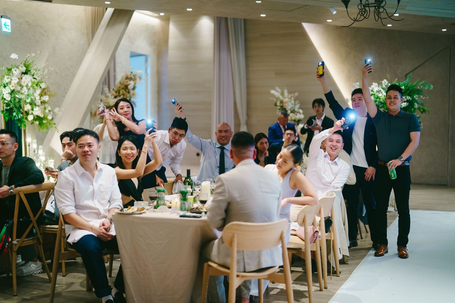 Professional business meeting around modern white conference tables with people seated and engaged in discussions.