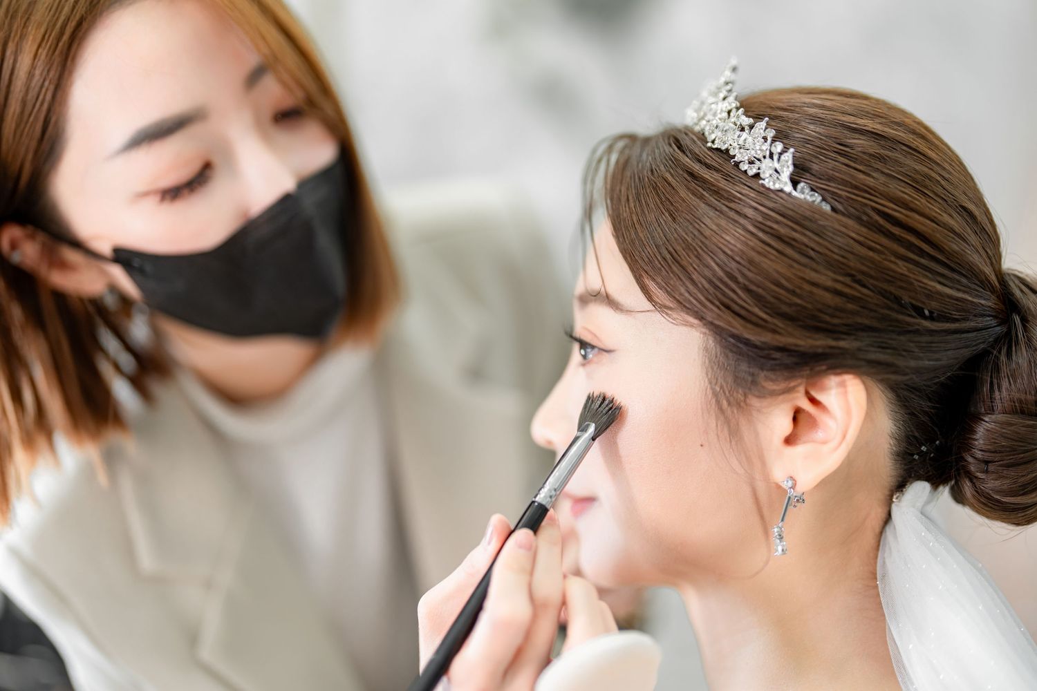 Professional makeup artist applying cosmetics with brushes and tools during a beauty treatment session.