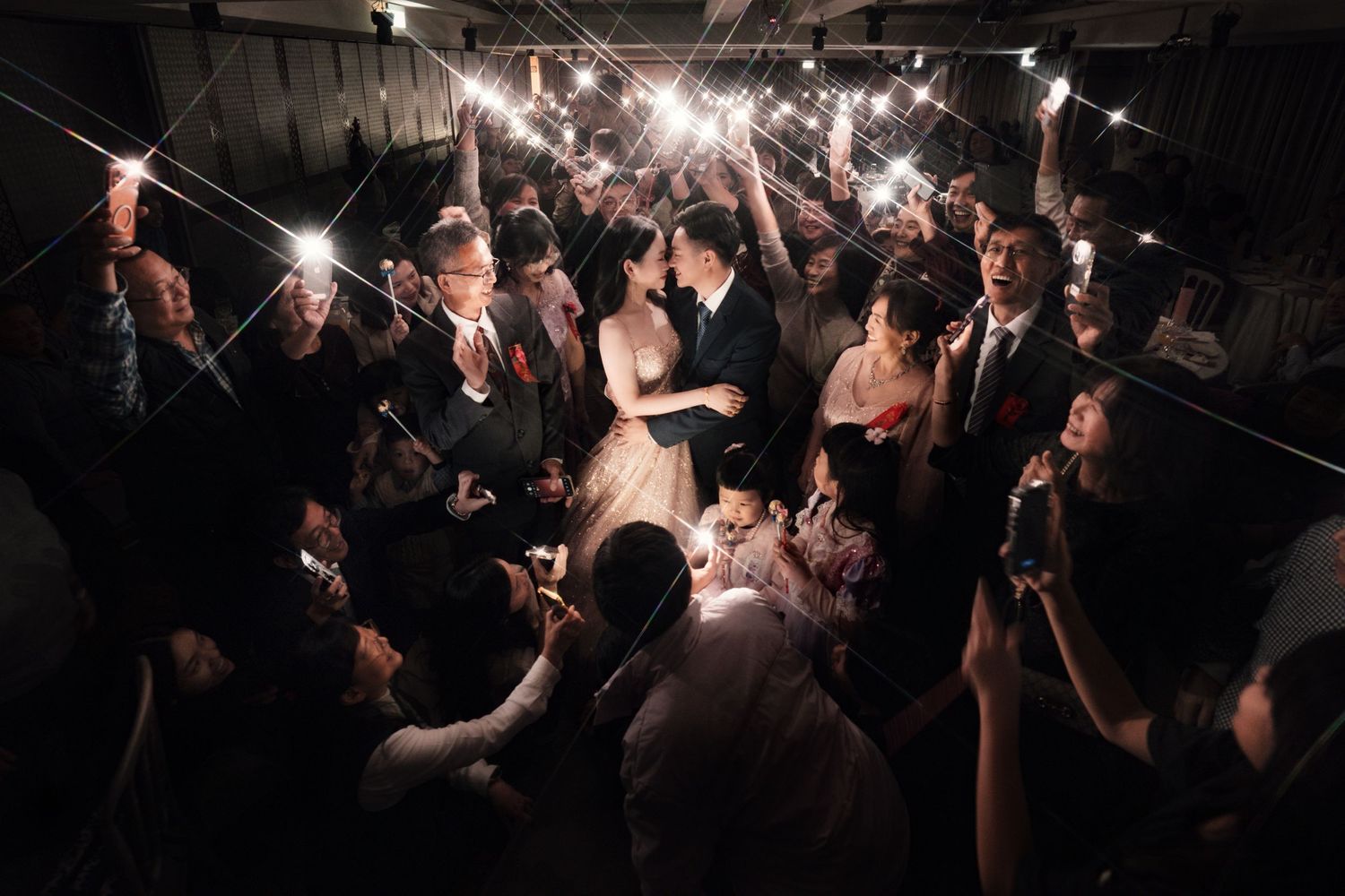 A dark concert venue filled with silhouettes of people dancing and celebrating under string lights.