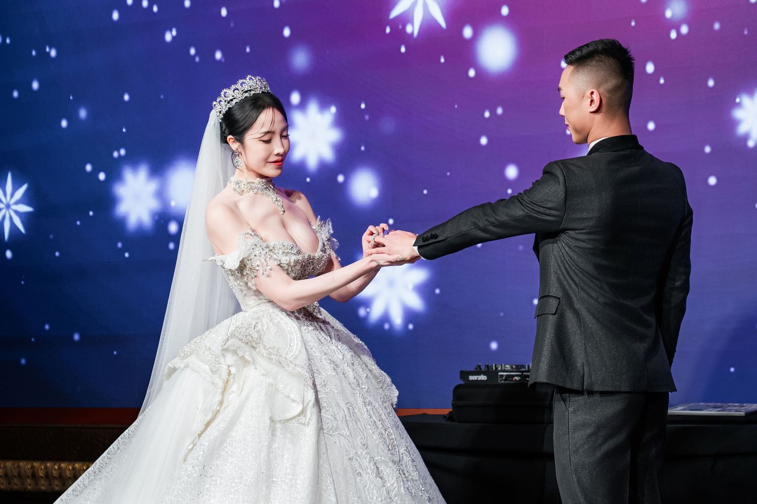 A couple shares their first dance at a wedding reception with a starry blue and purple backdrop.