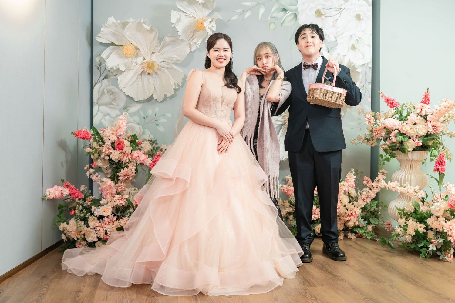 A group poses in formal attire against a floral backdrop at an elegant event.